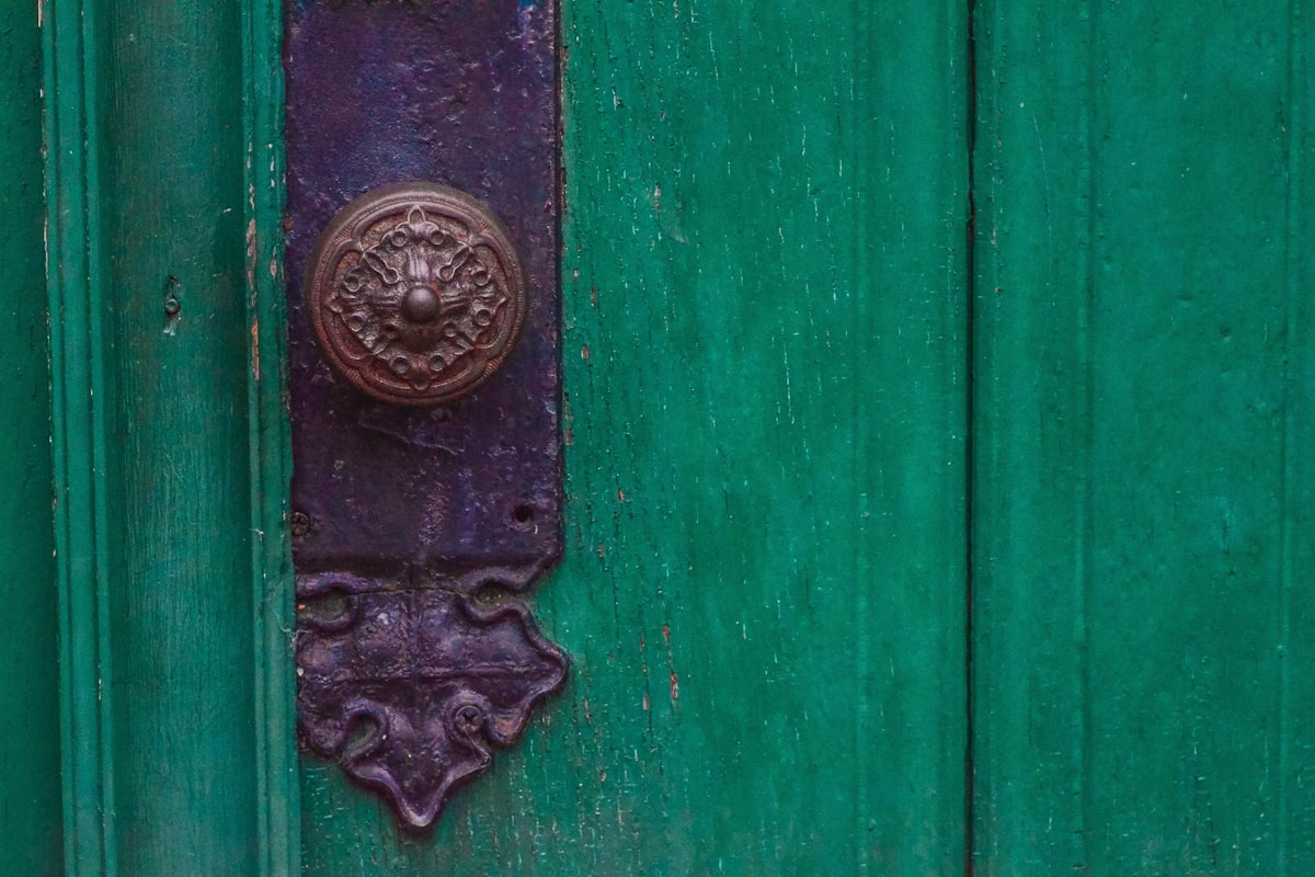 Une porte de bois vert et sa poignée de laiton ouvragée