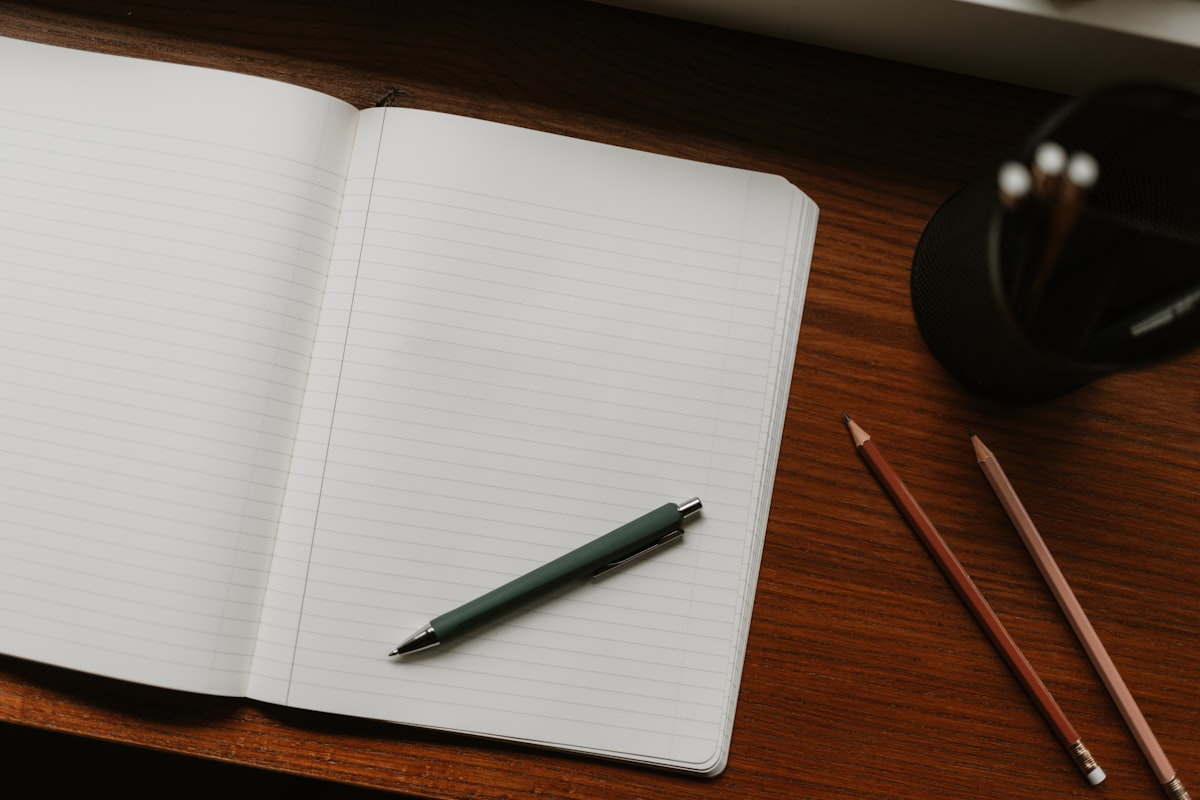 Un carnet ouvert à une page blanche, un stylo posé dessus