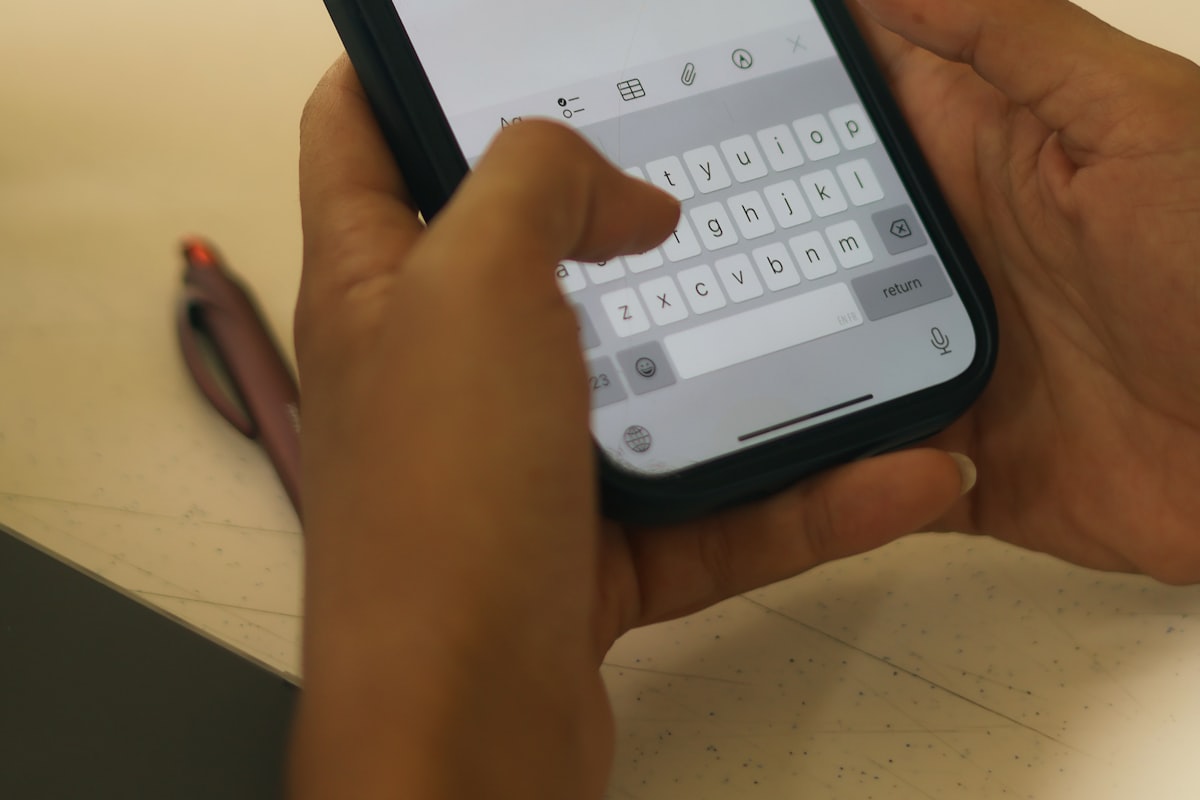 Deux mains tenant un téléphone, en train de taper un message